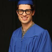 student in cap and gown takes a picture